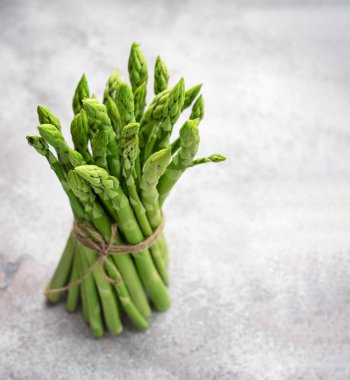 Gri beton arka planda taze yeşil kuşkonmaz. Düz yatıyordu