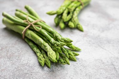 Gri beton arka planda taze yeşil kuşkonmaz. Düz yatıyordu