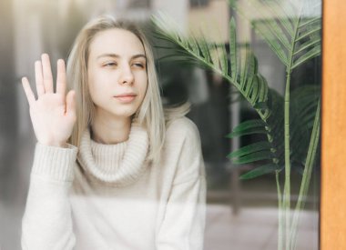 Pencerenin yanındaki üzgün kız bir şey düşünüyor. Stresli bayan kendini yalnız hissediyor.