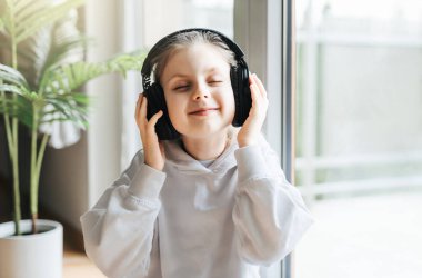 Evde kulaklıkla müzik dinleyen tatlı küçük kız..
