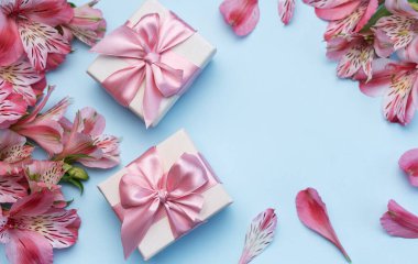 Tebrik metni çerçevesi, Alstroemeria çiçekleri ve mavi arka planda hediye kutuları. Doğal renklerde tebrik kartı. Alstromeria içeren metinler için arka plan. Düz yatış, üst görünüm.