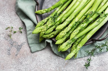 Gri beton arka planda taze yeşil kuşkonmaz. Düz yatıyordu