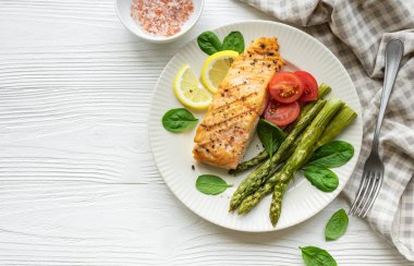 Pişmiş lezzetli somon, yeşil kuşkonmaz ve sebze tabağı. 