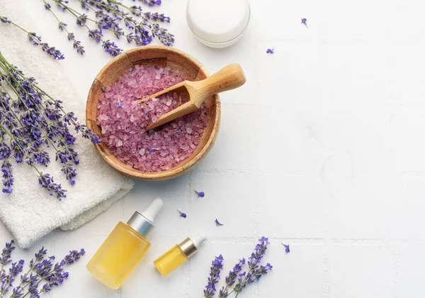 Lavender spa. Lavender salt, natural essential oil and fresh lavender on a white tile background.