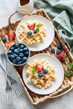 Beton gri arka planda çilek ve yaban mersinli taze pişmiş waffle. Ev yapımı pişirme..