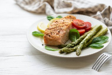 Pişmiş lezzetli somon, yeşil kuşkonmaz ve sebze tabağı. 