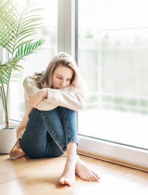 Pencerenin yanındaki üzgün kız bir şey düşünüyor. Stresli kadın kendini yalnız hissediyor