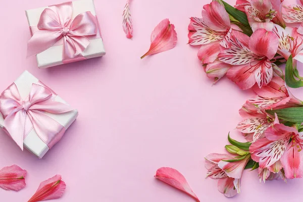Tebrik metni çerçevesi, Alstroemeria çiçekleri ve pembe arka planda hediye kutuları. Doğal renklerde tebrik kartı. Alstromeria içeren metinler için arka plan. Düz yatış, üst görünüm.