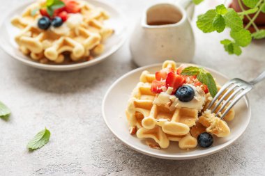 Beton gri arka planda çilek ve yaban mersinli taze pişmiş waffle. Ev yapımı pişirme..