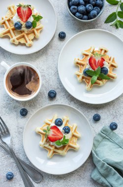 Beton gri arka planda çilek ve yaban mersinli taze pişmiş waffle. Ev yapımı pişirme..