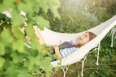 Küçük bir kız yazın bir hamakta dinlenir. Köyde yaz mevsimi. 