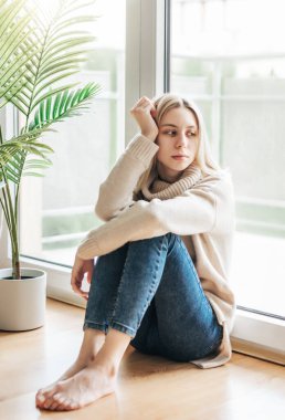 Pencerenin yanındaki üzgün kız bir şey düşünüyor. Stresli kadın kendini yalnız hissediyor