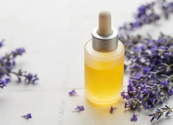 Lavender spa. Lavender  natural essential oil and fresh lavender on a white tile background.