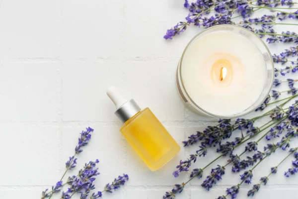 Lavender spa. Lavender  natural essential oil, aromatic candle and fresh lavender on a white tile background.