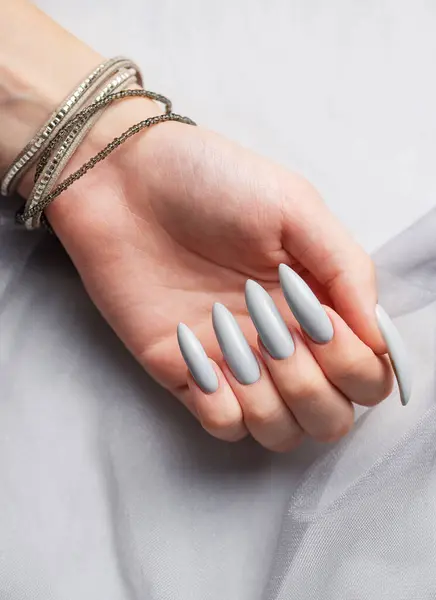 stock image Beautiful painted in grey nails on grey lace background.