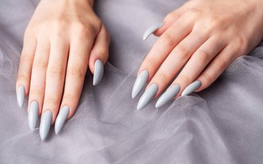 Gri dantelli arka planda gri tırnaklarla boyanmış güzel.