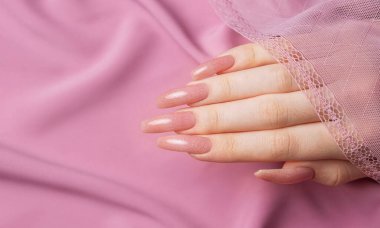 Pembe ipek üzerinde güzel manikürlü kadın elleri. 