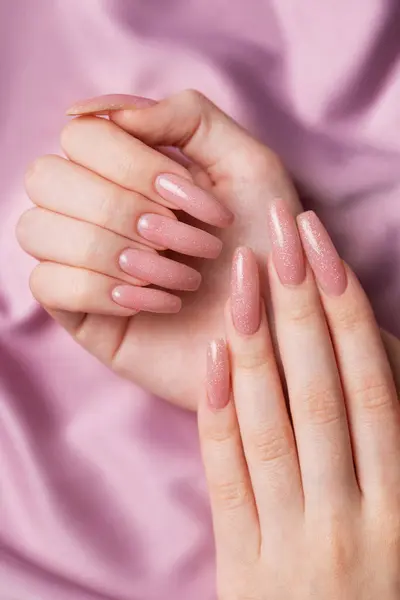 Female hands with beautiful manicure  on pink silk
