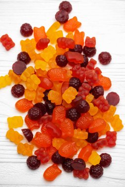 Çocuklar için vitaminler, beyaz ahşap arka planda jelibon şekerler.