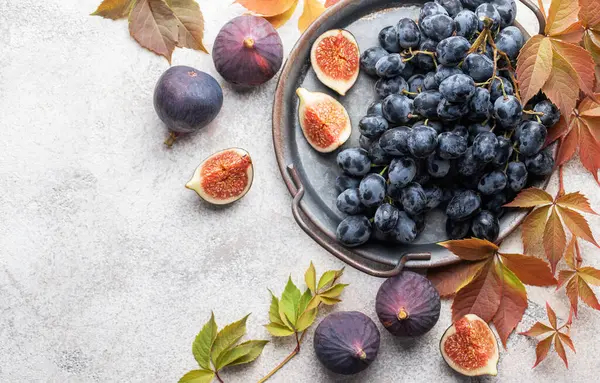 Taze incir ve sonbahar yapraklı koyu üzümler.