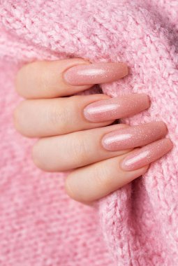 Pembe kazağında güzel manikürlü kadın elleri.