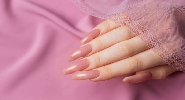 Pembe ipek üzerinde güzel manikürlü kadın elleri. 