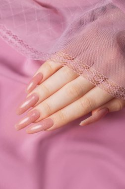 Pembe ipek üzerinde güzel manikürlü kadın elleri. 