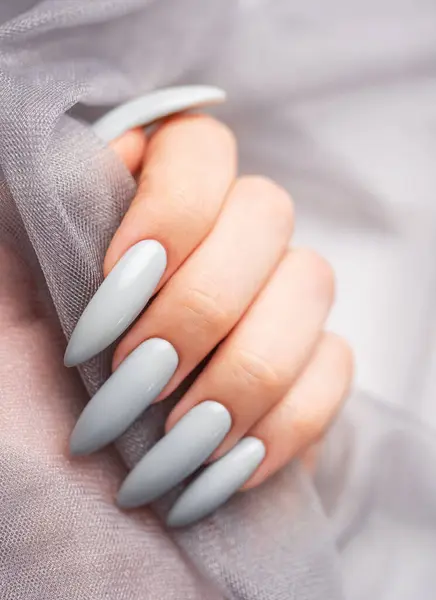 Beautiful painted in grey nails on grey lace background.