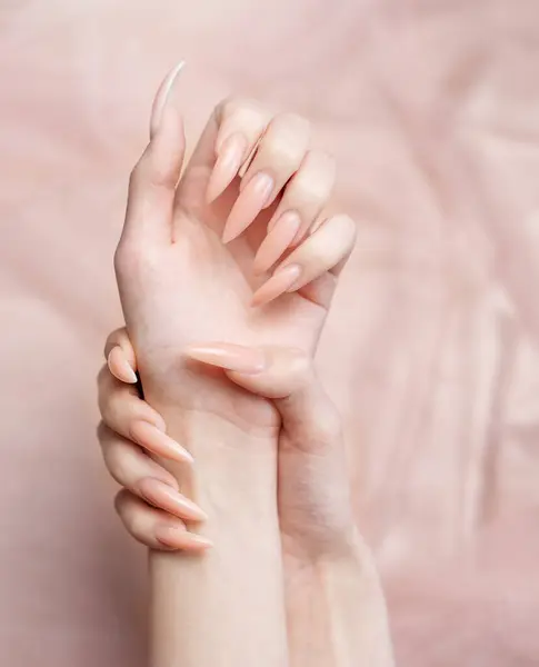 Elegante Pastellrosa Natürliche Maniküre Weibliche Hände Auf Rosa Seidenhintergrund lizenzfreie Stockfotos