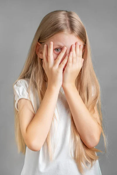 Ein Kleines Mädchen Bedeckt Ihr Gesicht Mit Den Händen Und lizenzfreie Stockbilder