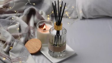 Aroma kokulu sazlık difüzyon camı kokulu mum ve yatağın üzerindeki çelenkle tepside.