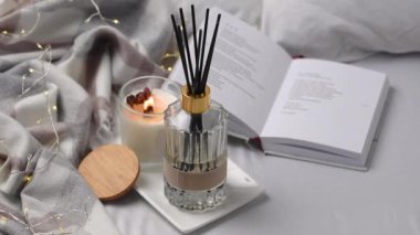 Aroma kokulu sazlık difüzyon camı kokulu mum ve yatağın üzerindeki çelenkle tepside.