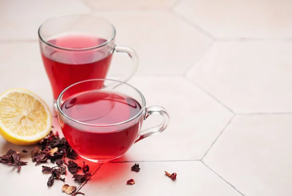 Glass cup of hot hibiscus tea and dried Hibiscus tea leaves.