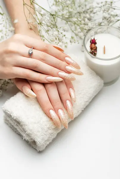 Manicured nails with pearlescent nail polish. The nails are covered with pearl gel polish on white background