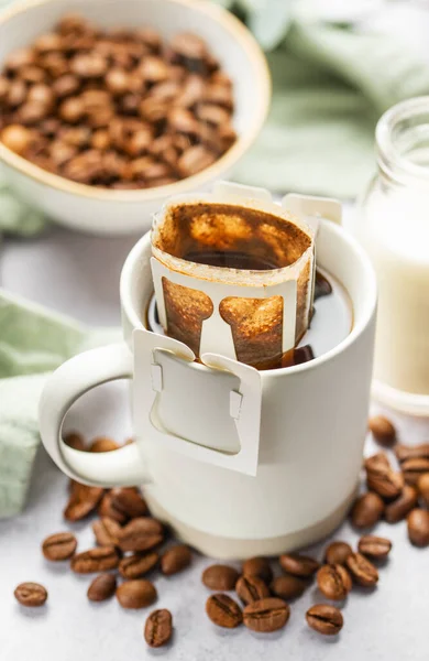 Drip coffee bag with ground coffee in cup.  Making freshly brewed coffee at home.