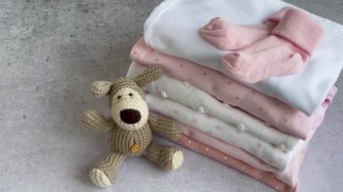 Bebek kıyafetleri yığını. Yavru örülmüş köpek oyuncağı, çocuklar için tulumların yanında. 