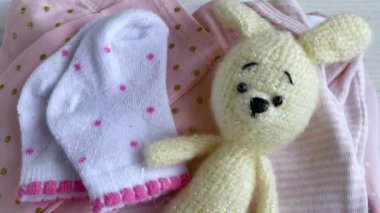 Bebek kıyafetleri yığını. Yavru örülmüş köpek oyuncağı, çocuklar için tulumların yanında. 