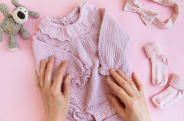 Oyuncak köpek, çorap ve saç bandıyla pembe bir beden. Yazın pembe arka planda bebek kıyafetleri ve aksesuarları. Yeni doğan moda. Düz yatış, üst yaşam