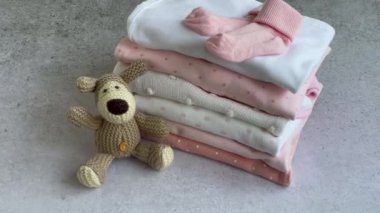 Bebek kıyafetleri yığını. Yavru örülmüş köpek oyuncağı, çocuklar için tulumların yanında. 
