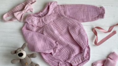 Oyuncak köpek, çorap ve saç bandıyla pembe bir beden. Yazın beyaz ahşap arka planda bebek kıyafetleri ve aksesuarlar. Yeni doğan moda. Düz yatış, üst görünüm