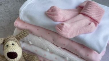 Bebek kıyafetleri yığını. Yavru örülmüş köpek oyuncağı, çocuklar için tulumların yanında. 