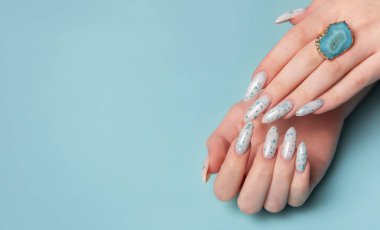 Mavi pastel arka planda mavi tırnak desenli kadın elleri. Mavi oje manikür.. 