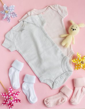 Bebek kıyafetleri, pantolonlar, çoraplar ve gri arka planda örülmüş oyuncaklar. Bebek kıyafetleri ve aksesuarlar. Düz yatış, üst yaşam