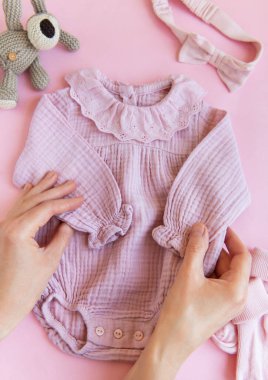 Oyuncak köpek, çorap ve saç bandıyla pembe bir beden. Yazın pembe arka planda bebek kıyafetleri ve aksesuarları. Yeni doğan moda. Düz yatış, üst yaşam