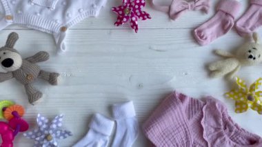 Yeni doğan bebek için beyaz kıyafetler ve aksesuarlar. Örgü oyuncaklar, örgü şamata, beyaz ahşap arka planda çoraplar. Bebek partisi konsepti. Düz yatış, üst görünüm