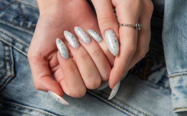 Kotun arka planında mavi tırnak desenli bir kadın eli. Mavi oje manikür.. 