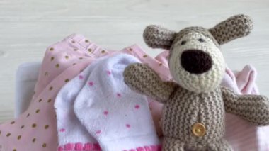 Bebek kıyafetleri yığını. Yavru örülmüş köpek oyuncağı, çocuklar için tulumların yanında. 