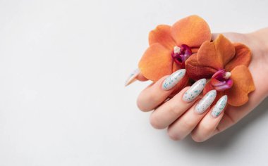 Beyaz arka planda mavi tırnak desenli bir kadın eli. Mavi oje manikür.