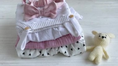 Bebek kıyafetleri yığını. Çocuk tulumunun yanında bebek örgü tavşan oyuncağı var.