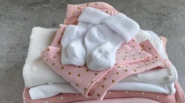Bebek kıyafetleri yığını. Çocuk tulumunun yanında bebek örgü tavşan oyuncağı var.
